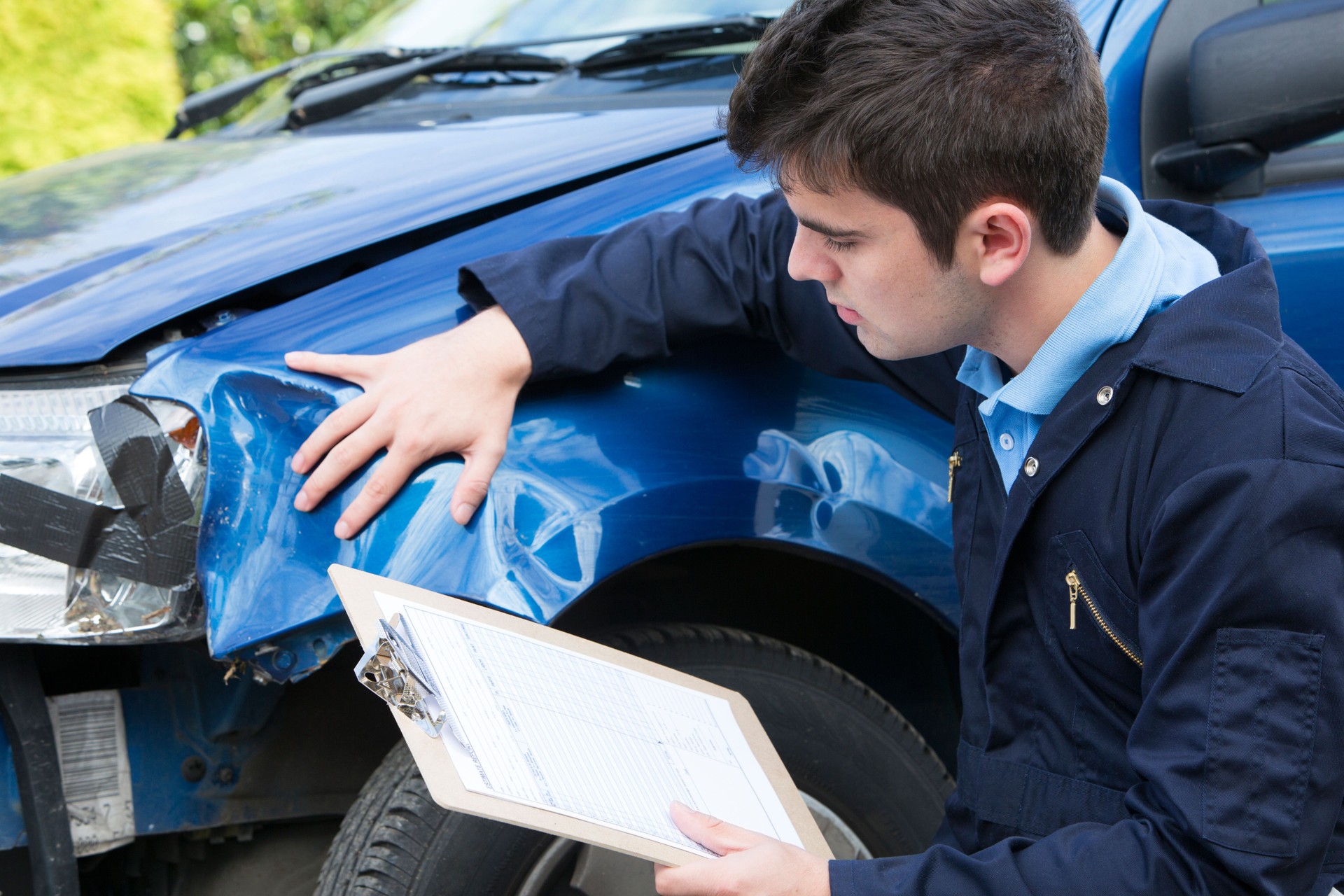 Auto Workshop Mechanic Inspecting Car And Filling In Repair Estimate